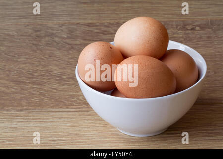 Una vaschetta di colore bianco pieno di freschi, punteggiate di uova su un tavolo di legno. Foto Stock