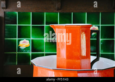 Vintage arancio lavabo e lavello con piastrelle verdi in background. Foto Stock