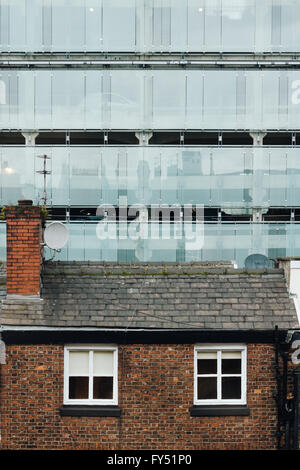 Vecchia casa di mattoni in primo piano e un moderno edificio di vetro nella parte posteriore di massa. Shudehill parcheggio auto in Manchester. Foto Stock