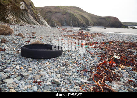 Vecchia auto pneumatico miscelato con driftwood, ramoscelli e alghe marine lavato fino a Traeth Penllech spiaggia presso l'alta marea Foto Stock