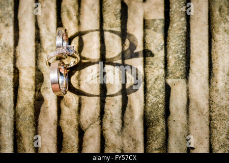 Oro anelli di nozze su pietra con luce laterale Foto Stock