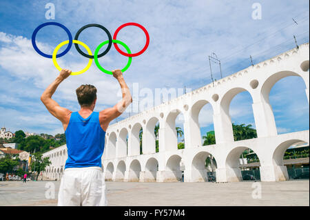 RIO DE JANEIRO - MARZO 29, 2016: atleta holding anelli olimpici sorge all'aperto nella plaza presso la famosa Lapa archi landmark. Foto Stock