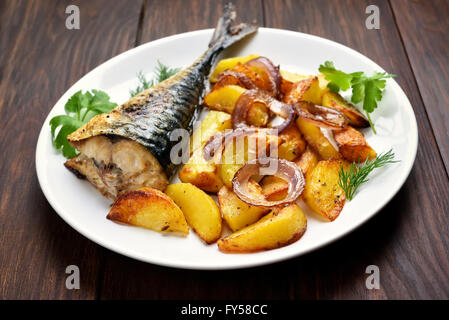 Patate al forno cunei e sgombro pesce sulla piastra bianca Foto Stock