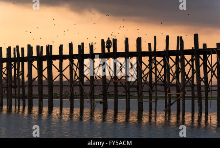 Tramonto sull'U Bein ponte che attraversa il lago Taungthaman, la più lunga passerella in legno di teak nel mondo Foto Stock