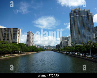 Ala Wai Canal, alberghi condomini e alberi in una bella giornata di Waikiki di Oahu, Hawaii con montagne in lontananza. L'Ala Wai Ca Foto Stock