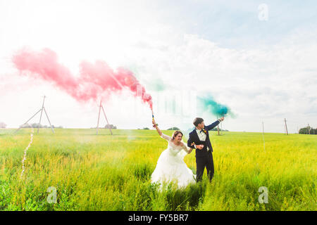 La sposa e lo sposo con il fumo delle bombe sul prato Foto Stock