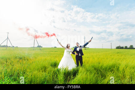 La sposa e lo sposo con il fumo delle bombe sul prato Foto Stock