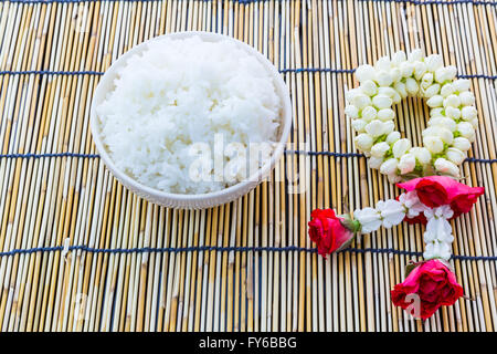 Vapore tailandese riso sul tappetino di bambù con una ghirlanda decorazione Foto Stock