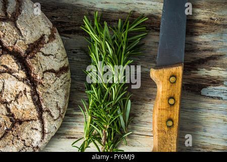 Il pane artigianale focaccia, rosmarino e il coltello, piatto adagiare sulla tavola di legno Foto Stock