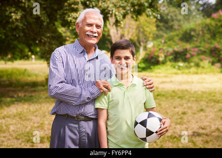 Il nonno di trascorrere del tempo con il nipote: Ritratto di uomo anziano a giocare a calcio con il nipote nel parco. Il vecchio uomo abbraccia t Foto Stock