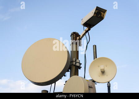 Mazzetto di trasmettitori e di antenne sulla torre di telecomunicazione durante il tramonto Foto Stock