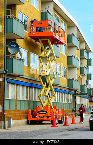 Trelleborg, Svezia - 12 Aprile 2016: i lavoratori sulla parte superiore di un Riwal elevatore a pantografo piattaforma in grado di eseguire alcune riparazioni della finestra al di fuori di un Foto Stock