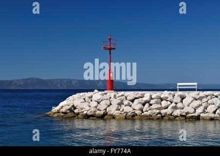 Faro rosso in porto con pietre e banco di bianco. podgora, Croazia. Foto Stock