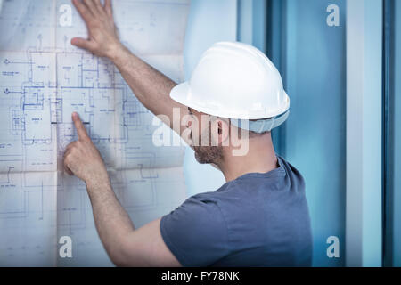 Ritratto di un architetto builder studiando piano di disposizione delle camere, serio ingegnere civile che lavora con i documenti Foto Stock