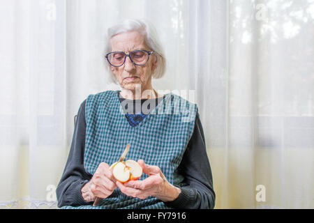 Novanta anni nonna la tranciatura e la sfogliatura di un Apple in ambienti interni Foto Stock