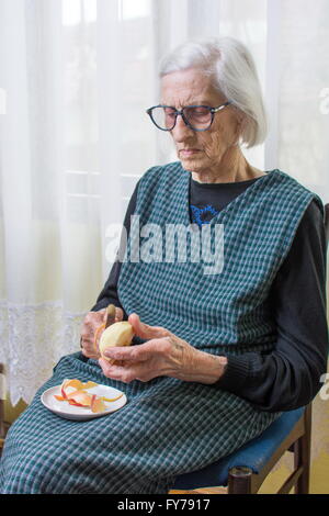 Novanta anni nonna la tranciatura e la sfogliatura di un Apple in ambienti interni Foto Stock