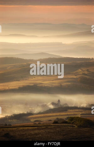Vista di una valle di prima mattina con la nebbia tra le colline Foto Stock