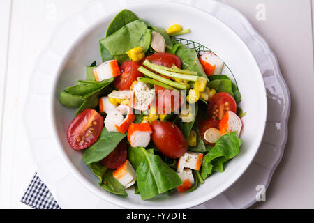 Insalata di spinaci con pomodorini e mais in ciotola bianco sul tavolo di legno Foto Stock