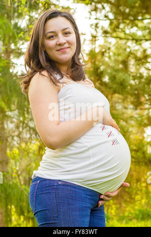 Ritratto di gravidanza sorridente giovane donna all'aperto in un caldo giorno d'estate. Foto Stock