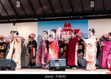 Giapponese primavera Kumamoto Cherry Blossom Festival, spettacolo teatrale, quattro geisha in kimono dancing, con fila di musicisti in costume tradizionale dietro. Foto Stock