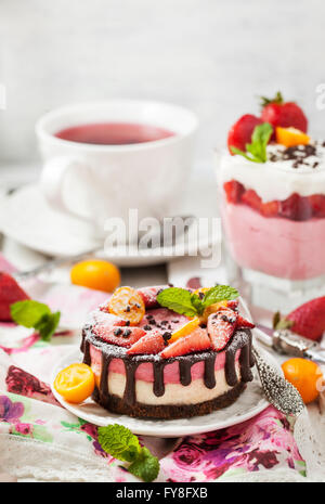 Deliziosa singoli mini torta (cheesecake) decorato con cioccolato e fragola Foto Stock