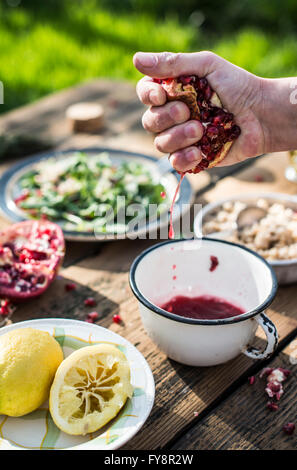 La preparazione di insalata verde con melograno, manna groppa e cipollina, spremitura melograno, spogliatoio Foto Stock