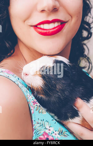 Vista posteriore della giovane donna con la Guinea Pig sulla sua spalla Foto Stock