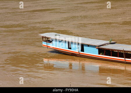 Blu e rosso barca lunga su marrone del fiume Mekong, Luang Prabang, Laos. Foto Stock