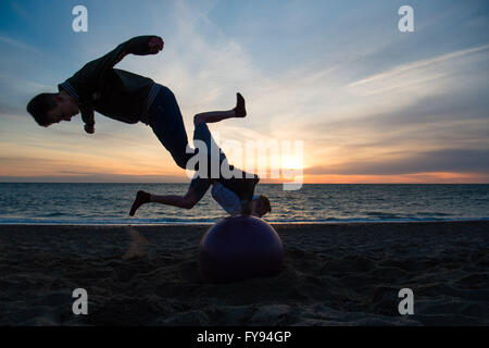 Aberystwyth Wales UK, sabato 23 aprile 2016 UK meteo: Come il sole tramonta su Cardigan Bay in Aberystwyth alla fine di una giornata di sole, ma freddi venti del nord, gli adolescenti BILLY Ashton and STACY WARREN, durante un weekend da Birmingham, eseguire salti acrobatici in aria fuori dalla spiaggia. Photo credit: Keith Morris/Alamy Live News Foto Stock