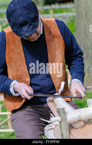 Un artigiano del legno utilizza un spokeshave (disegnare piano) a circa attorno a un pezzo di legno. Foto Stock