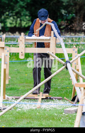 Un artigiano del legno utilizza un piede-powered tornio manuale a sua volta un pezzo di legno. Foto Stock