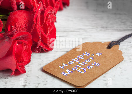 Felice Festa della Mamma testo con wet rose rosso su bianco tavola in legno rustico Foto Stock