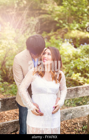 Aspettano di mamma e papà la tenuta di ciascun altro mentre godendo una bella giornata fuori. Luce di Haze effetto applicato per l'immagine. Foto Stock