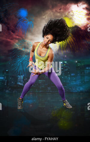 Giovane donna alla danza fitness di fronte a fuochi d'artificio Foto Stock
