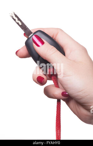 Stretta di mano curati con red Nail Polish holding nero auto chiave su sfondo bianco Foto Stock