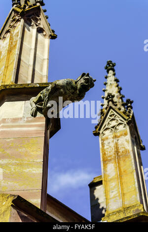 Gargoyle su una cattedrale gotica, il dettaglio di una torre sul cielo azzurro sfondo, Saint Florent chiesa, Niederhaslach, Francia Foto Stock