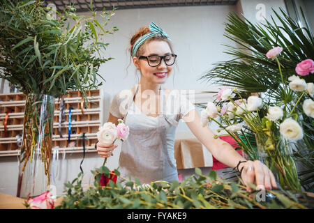 Felice bella giovane donna fioraio rendendo bouquet nel negozio di fiori Foto Stock