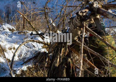 Un soldato o sniper tenendo la pistola con schermo virtuale proiezione e mirando in foresta Foto Stock