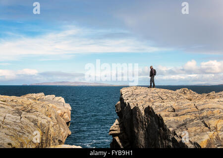 Rosbeg, County Donegal, Irlanda meteo. Il 24 aprile 2016. Una ortesi per l'Irlanda "Wild Atlantic modo' ammira la vista sull'oceano su un ventoso ma giornata di sole. In fondo è Arranmore Island. Credito: Richard Wayman/Alamy Live News Foto Stock