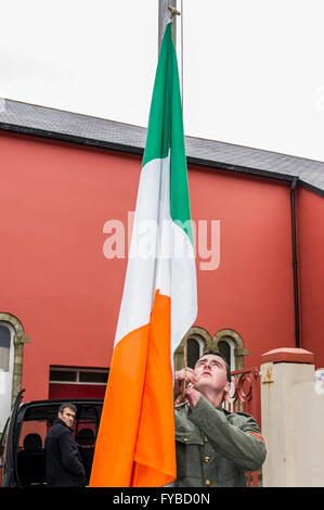 Skibbereen, Irlanda. 24 Aprile, 2016. Ian Lynch, diretto discendente del combattente ribelle Gearóid O'Sullivan, solleva il tricolore irlandese durante la misericordia altezze della scuola Annuncio evento della durata di un giorno per commemorare i 100 anni dall'inizio della ribellione in Dublino. Credito: Andy Gibson/Alamy Live News Foto Stock