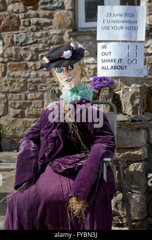 Le donne di paglia in abito viola in Wray, Lancashire, Regno Unito XXV Aprile, 2016. Brexit UE voto referendario a Wray annuali di Spaventapasseri Festival. Gli abitanti del villaggio sono nuovamente di aver creato alcuni strani e bizzarri e meravigliosi spaventapasseri creazioni di sorprendere i visitatori. con creazioni che appaiono sui giardini del villaggio. Foto Stock