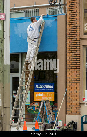 Giovane pittura blu sulla parete edilizia-Victoria, British Columbia, Canada. Foto Stock