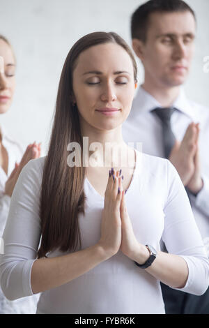 Business e stile di vita sano concetto. Ritratto di giovane di impiegati in piedi di yoga posa al posto di lavoro. Gruppo di attività Foto Stock