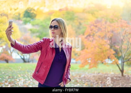 Pretty Woman facendo selfie in autunno park Foto Stock