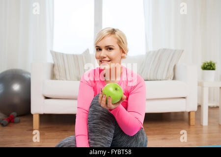 Donna felice di mangiare mela verde a casa Foto Stock