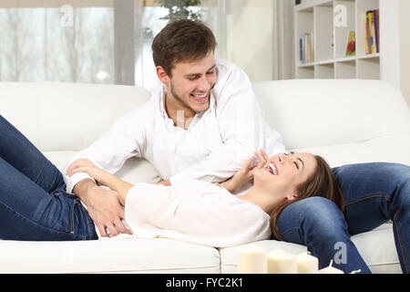 Giocoso giovane o matrimonio solletico e ridere in un lettino a casa Foto Stock