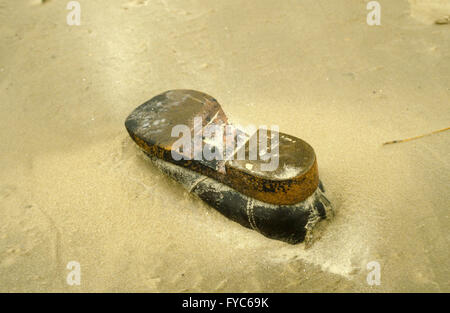 Vecchia scarpa nella sabbia come jetsam presso la spiaggia dell'isola danese Rømø. Foto Stock