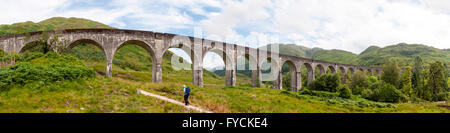 Escursionista sotto il viadotto Glenfinnan, arcuato il ponte ferroviario sul West Highland Line, Lochaber, Scotland, Regno Unito Foto Stock