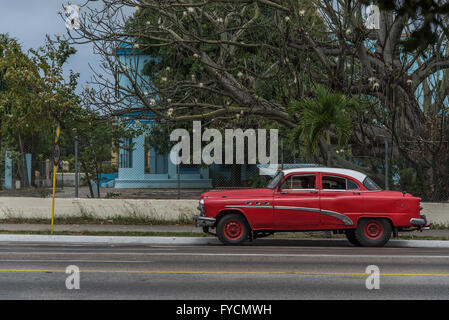 Vivace colore rosso brillante splendidamente mantenuta classic American Automobile con autista dando un tour della città intorno a La Habana, Havana, Cuba. Foto Stock