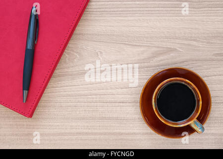 Tazza di caffè e un notebook con la penna sulla scrivania di legno Foto Stock